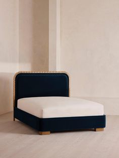 an upholstered bed with gold studding on the headboard and foot board