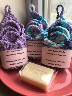 three crocheted bags sitting on top of a pink plate next to a bar of soap