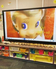 a large flat screen tv mounted to the side of a wall next to toy bins