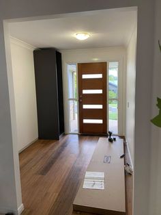 an empty room with wood flooring and a wooden door in the center is being installed