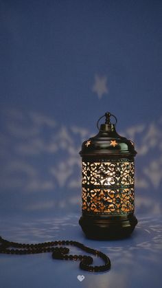 a lit candle on a table with a chain attached to it and a star in the background