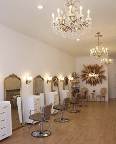 In a Boho salon setting, beige salon-styling chairs stand in front of white stations with gold hardware and large mirrors. Shabby Chic Salon Ideas, Two Station Salon Suite, Full Length Mirror Salon Station, Boho Style Salon, Boho Glam Salon, Hair Station, Vintage Hair Salon Decor, High End Salon