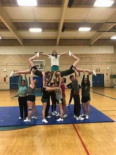 a group of young people standing on top of each other in a gym with one person doing a handstand