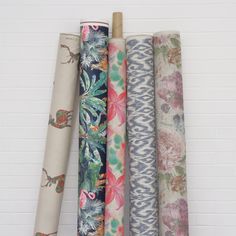 four rolls of fabric hanging on a white brick wall next to each other in different patterns