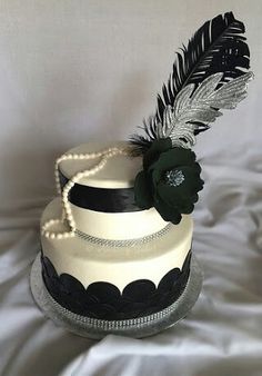 a white and black cake with a feather on it's top sitting on a bed