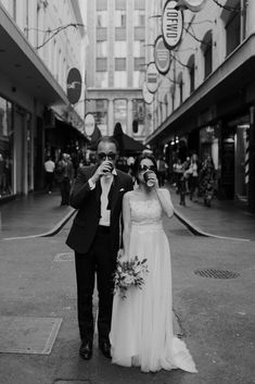 a man and woman standing next to each other in front of tall buildings on a city street