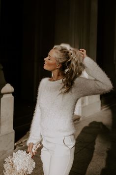 a woman in white is walking down the street with her hair in a pony tail