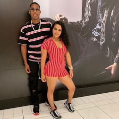 a man and woman posing in front of a wall with a movie poster behind them