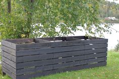 a large wooden planter sitting on top of a lush green field next to a lake