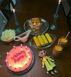 a wooden table topped with two plates filled with cake and corn on the cob