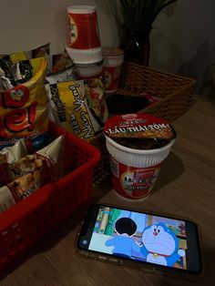 a cell phone sitting on top of a wooden table next to a basket filled with food