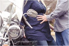 a pregnant woman standing next to a motorcycle with her hands on the handlebars