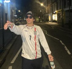 a man is standing on the street with his arms out and holding onto a bottle