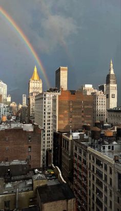 a rainbow in the sky over a city with tall buildings