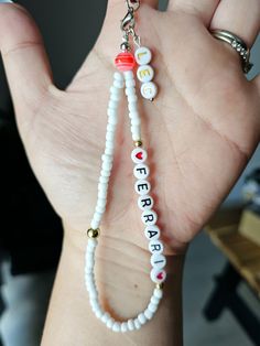 a hand holding a white beaded necklace with letters on it