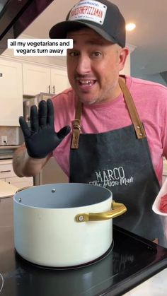 a man in an apron and hat holding up his hands while standing next to a pot