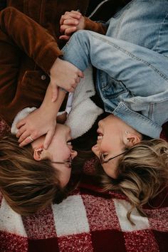 two young women laying on top of each other with their hands in the air together