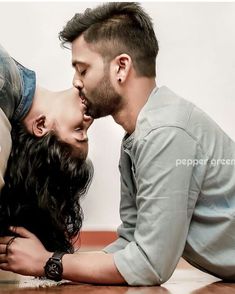 a man kissing a woman on the cheek while laying on the floor with his arm around her head