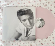 a pink and white photo of elvis presley on a floral print sheet with a flowered background