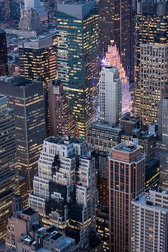 an aerial view of skyscrapers at night in new york city, with the empire building lit up