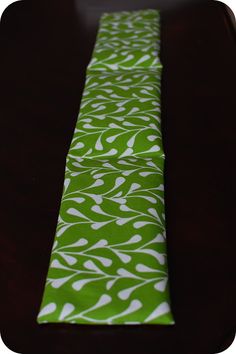 a green and white tie sitting on top of a wooden table