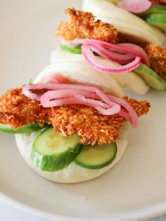 small sandwiches with onions, cucumbers and pickles are on a white plate