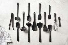 black kitchen utensils lined up on a white surface