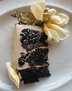 a piece of cake with frosting and flowers on it sitting on a white plate