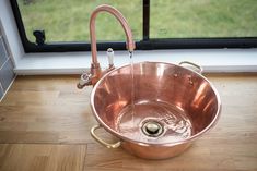 a large copper sink in front of a window