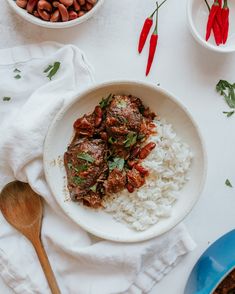 a white bowl filled with rice and meat next to two bowls full of chilis