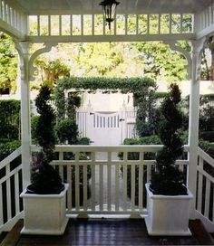 a white gazebo with potted plants on the porch