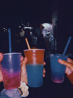 three people holding up two different colored cups with straws in their hands and one is blue, the other red