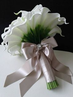 a bouquet of white flowers with a ribbon tied around it on top of a table