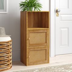 a wooden cabinet with a potted plant in it next to a basket on the floor