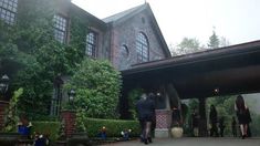 several people are standing in front of a large house with ivy growing on the walls