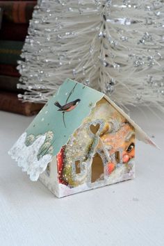 a small birdhouse sitting on top of a table next to a white christmas tree