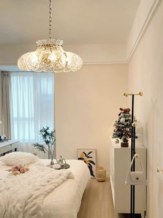 a bedroom with a white bed and chandelier hanging from it's ceiling