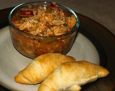 two croissants on a plate next to a bowl of food