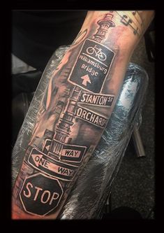 a man's arm with street signs on it and a stop sign in the middle