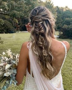 the back of a woman's head wearing a wedding dress and holding a bouquet