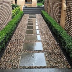 an outdoor walkway made out of bricks and stones with water running down the path between them