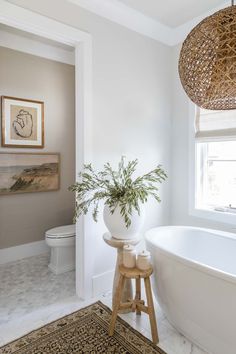 a white bath tub sitting next to a toilet in a bathroom under a light fixture