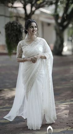 a woman in a white sari standing on the street