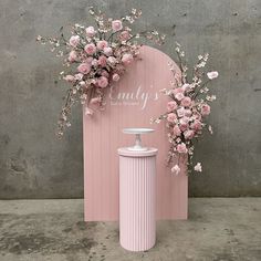 a pink vase with flowers next to a pink sign