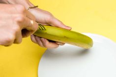 a person is peeling a banana on a yellow and white plate with the peel removed