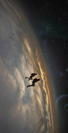 two people are flying in the sky with clouds and sun behind them as seen from space