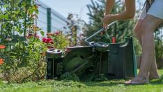 a woman is mowing the grass in her yard with an electric lawn mower