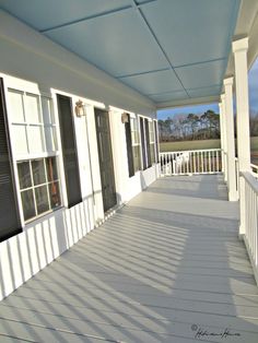 an empty porch with white siding and black shutters on the front of the house