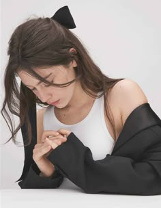 a woman sitting on the floor with her hands folded over her chest and looking down