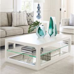 a white coffee table with two vases sitting on it's sides and a couch in the background